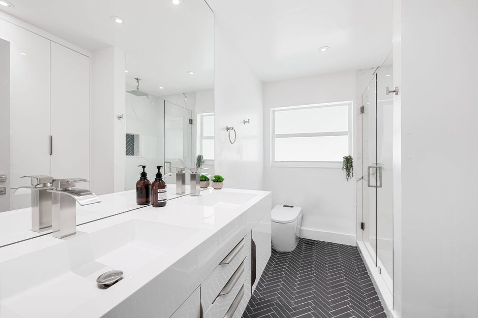Modern white bathroom featuring sleek fixtures and herringbone flooring design.