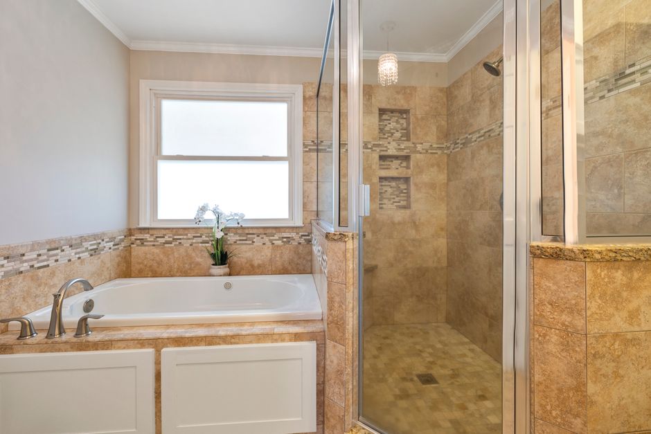 A stylish bathroom featuring a bathtub and a glass-enclosed shower with elegant tile design.